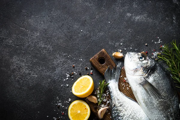 Färsk fisk dorado på svart sten bord. — Stockfoto