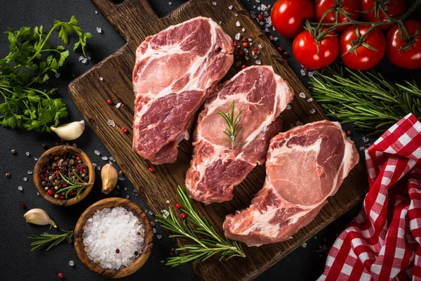 Varkensvlees aan houten plank op zwarte tafel. — Stockfoto