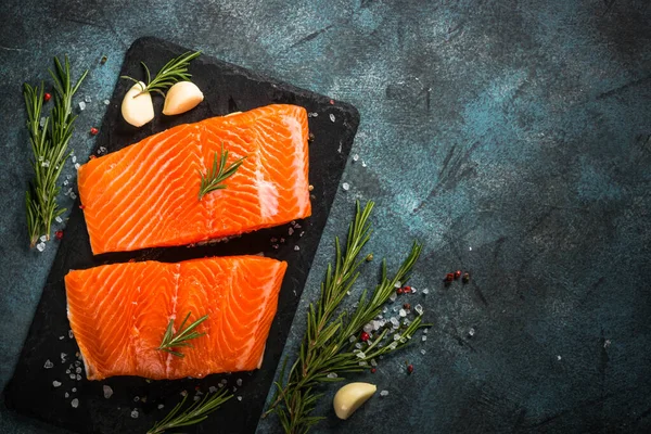 Pescado salmón con ingredientes a la mesa negra. — Foto de Stock