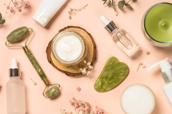 Kosmetické výrobky - Jade válec a gua sha masážní krém a sérum láhve na pastelovém pozadí. — Stock fotografie