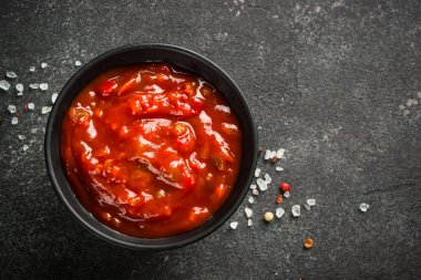 Siyah taş masadaki bir kasede domates sosu..