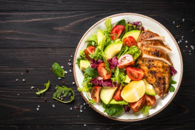 Ahşap masada taze salata ve ızgara tavuk..