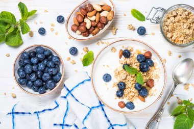 Beyaz ahşap masada taze yaban mersinli yoğurt taneciği..