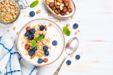 Beyaz ahşap masada taze yaban mersinli yoğurt taneciği..
