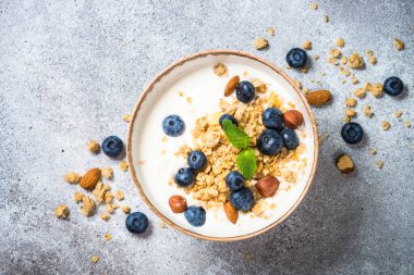 Taş masada taze yaban mersinli yoğurt taneleri..