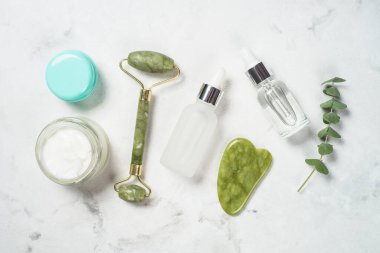 Yeşim silindirli ve gua sha taş masajcısı kozmetik ürünleri ile.