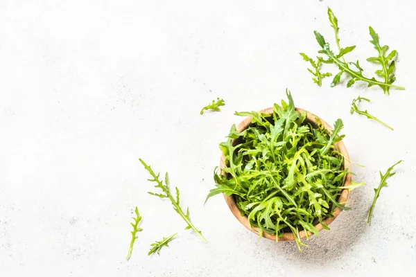 Arugula beyaz masada taze yeşil yapraklar.