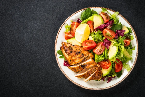 Grilled chicken with fresh salad at black table. — Stock Photo, Image