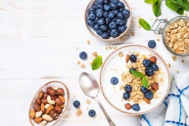 Beyaz ahşap masada taze yaban mersinli yoğurt taneciği..