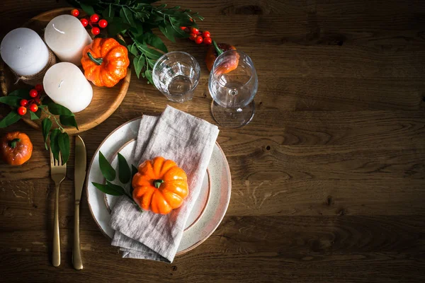 Nastavení podzimního stolu s talířem, dýní a svíčkami. — Stock fotografie