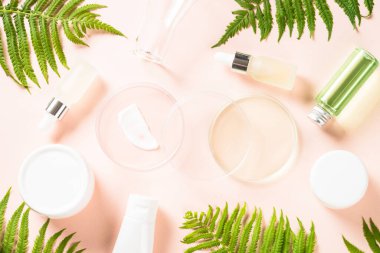 Kozmetik ürünleri ve yeşil bitkilerle dolu cam petri kabı.