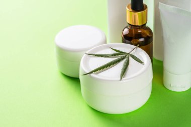 Yeşil arka planda esrar kozmetik ürünleri yakın plan.