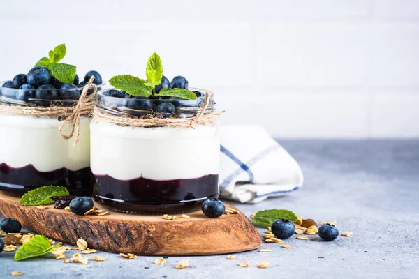 Parfait con arándanos, granola y mermelada en dos frascos de vidrio. — Foto de Stock