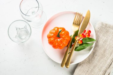 Sonbahar sofrası beyaz tabak, altın çatal bıçak ve sonbahar süslemeleri..