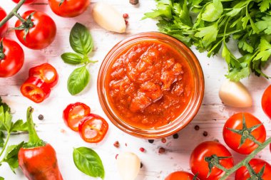 Beyaz arka planda otlu domates sosu ve baharatlar.