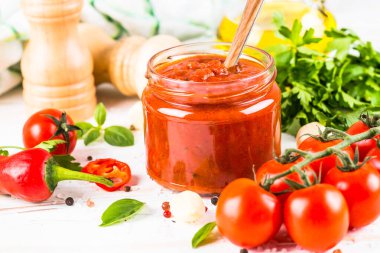 Beyaz arka planda otlu domates sosu ve baharatlar.