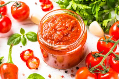 Beyaz arka planda otlu domates sosu ve baharatlar.