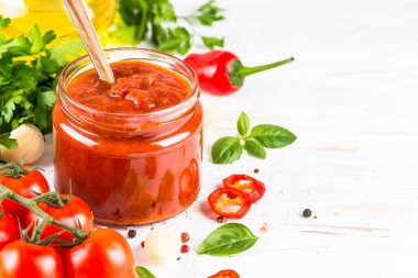 Beyaz arka planda otlu domates sosu ve baharatlar.