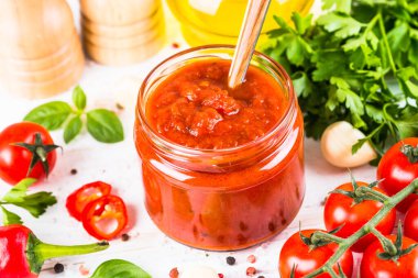 Beyaz arka planda otlu domates sosu ve baharatlar.