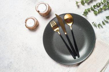 Beyaz tabak, çatal bıçak ve okaliptüslü masa ayarları .