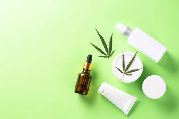 Produtos cosméticos Cannabis sobre fundo verde vista superior. — Fotografia de Stock