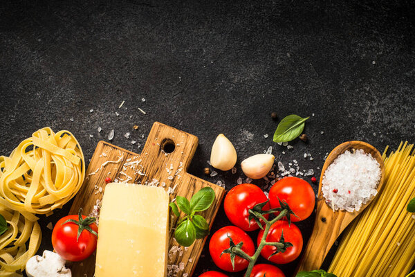 Pasta ingredients on black background top view.