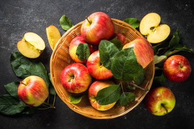 Beyaz masadaki sepetin içinde taze kırmızı elmalar.