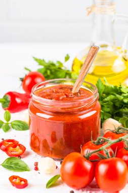 Beyaz arka planda otlu domates sosu ve baharatlar.