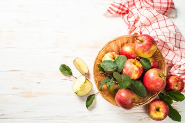Beyaz masadaki sepetin içinde taze kırmızı elmalar.