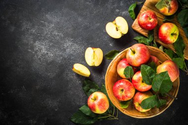 Beyaz masadaki sepetin içinde taze kırmızı elmalar.
