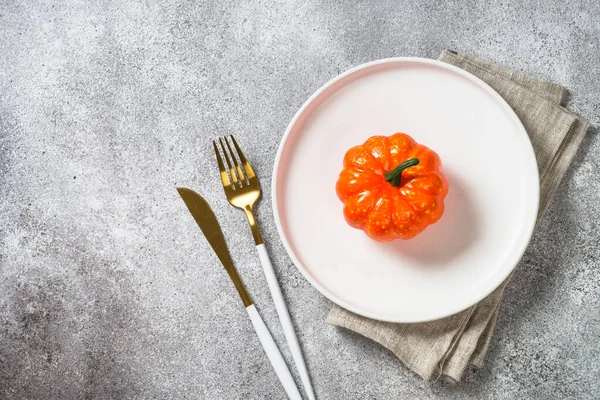 Mesa de otoño con plato blanco, cubiertos dorados y calabaza. —  Fotos de Stock