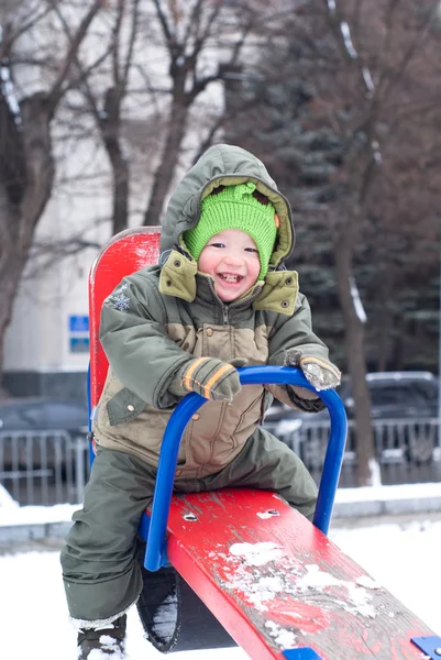 Маленький мальчик на качелях зимой — стоковое фото