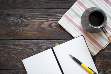 Defter, kalem ve kahve potu masaya