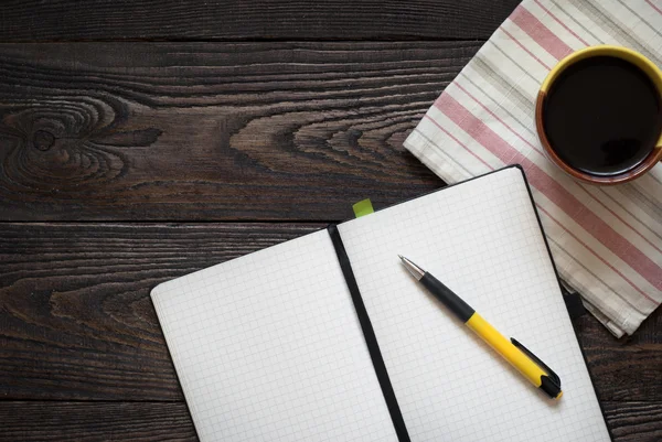 Poznámkový blok, tužku a kávu hrnce na stůl — Stock fotografie