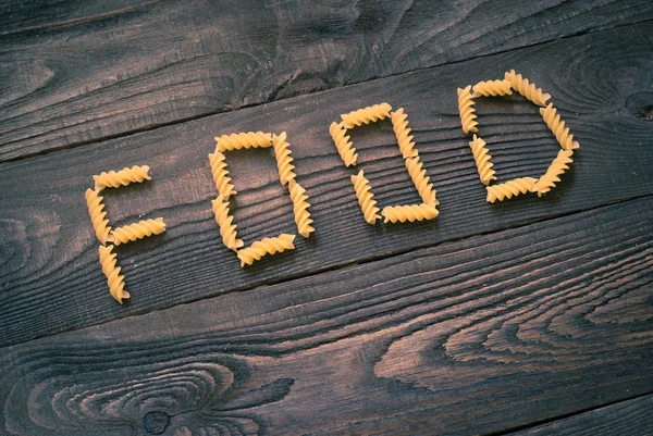 Word FOOD written pasta on the wooden table — Stock Photo, Image