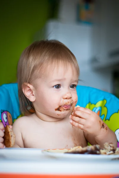 Gyermek megeszi tortát a magasszékben — Stock Fotó