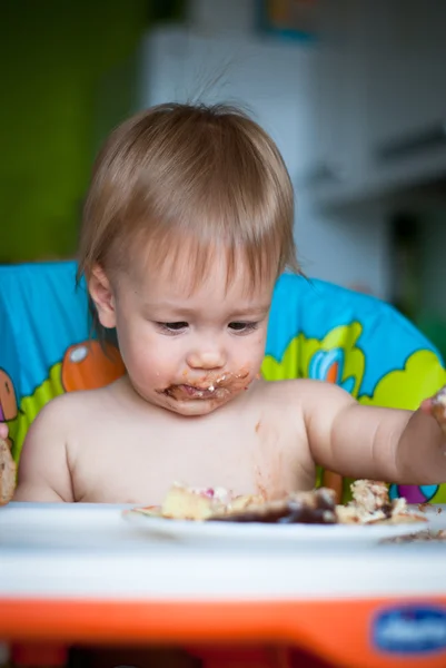 Kind eet cake in de hoge stoel — Stockfoto