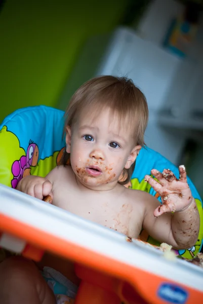 Kind eet cake in de hoge stoel — Stockfoto