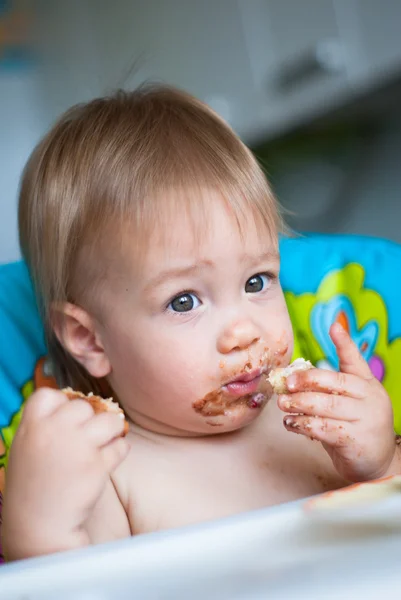 Criança come bolo na cadeira alta — Fotografia de Stock