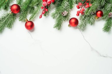 Noel arkaplanı beyazı üzerine kuruluydu. Noel kırmızı süslemeleri ve köknar ağacı. Kopyalama alanı olan kompozisyon.