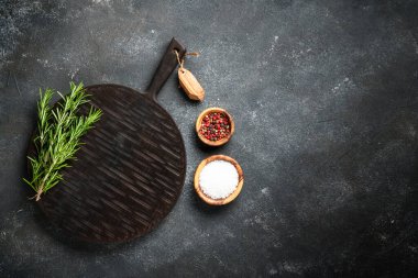 Mutfak aletleri, otlar ve baharatlarla siyah arka planda kesim tahtası. Kopyalama alanı olan üst görünüm.