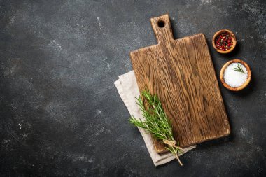 Mutfak aletleri, otlar ve baharatlarla siyah arka planda kesim tahtası. Kopyalama alanı olan üst görünüm.