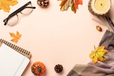 Cozy Autumn flat lay background. Notepad, candle, scarf and fallen leaves.