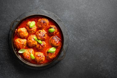 Meatballs in black plate on black stone background. Top view with space for text.
