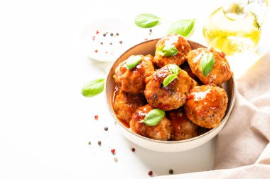 Beyaz masanın üstünde domates soslu köfte. Metin için boşluk ile kapat.