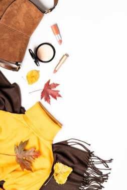 Sonbahar kumaşı ve aksesuarları beyaz arka planda. Atkı, kazak, çanta ve yapraklı kozmetik ürünler. Dizayn için alanı olan düz uzandı.