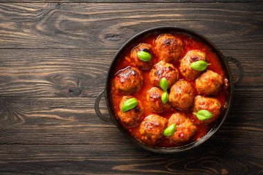 Ahşap masada fesleğen yapraklı domates soslu köfte. Üst görünüm, tasarım için alan.