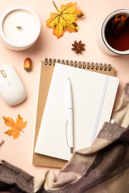 Sonbahar ofis masası. Dizüstü bilgisayar, defter, sıcak çay ve dökülen yapraklı eşarp. Üst görünüm, dikey.