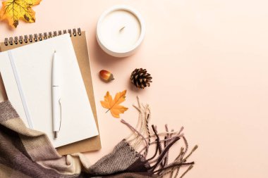 Cozy Autumn flat lay background. Notepad, candle, scarf and fallen leaves.