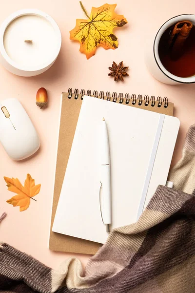 Sonbahar ofis masası. Dizüstü bilgisayar, defter, sıcak çay ve dökülen yapraklı eşarp. Üst görünüm, dikey.